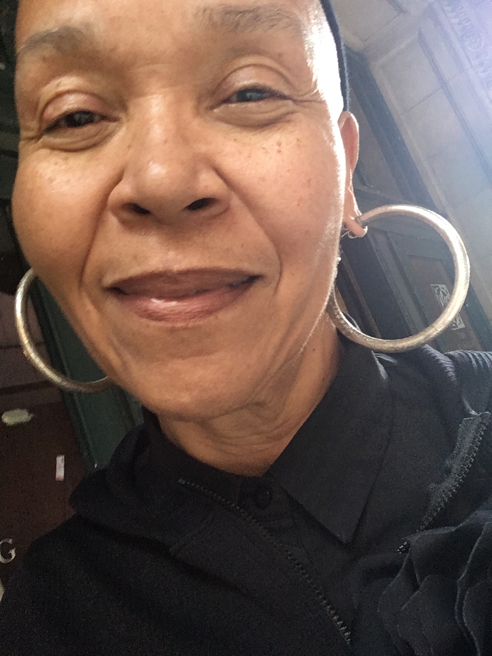 Facial portrait of Dorothy Perry light African American woman in black hat and large silver hoop earrings. 